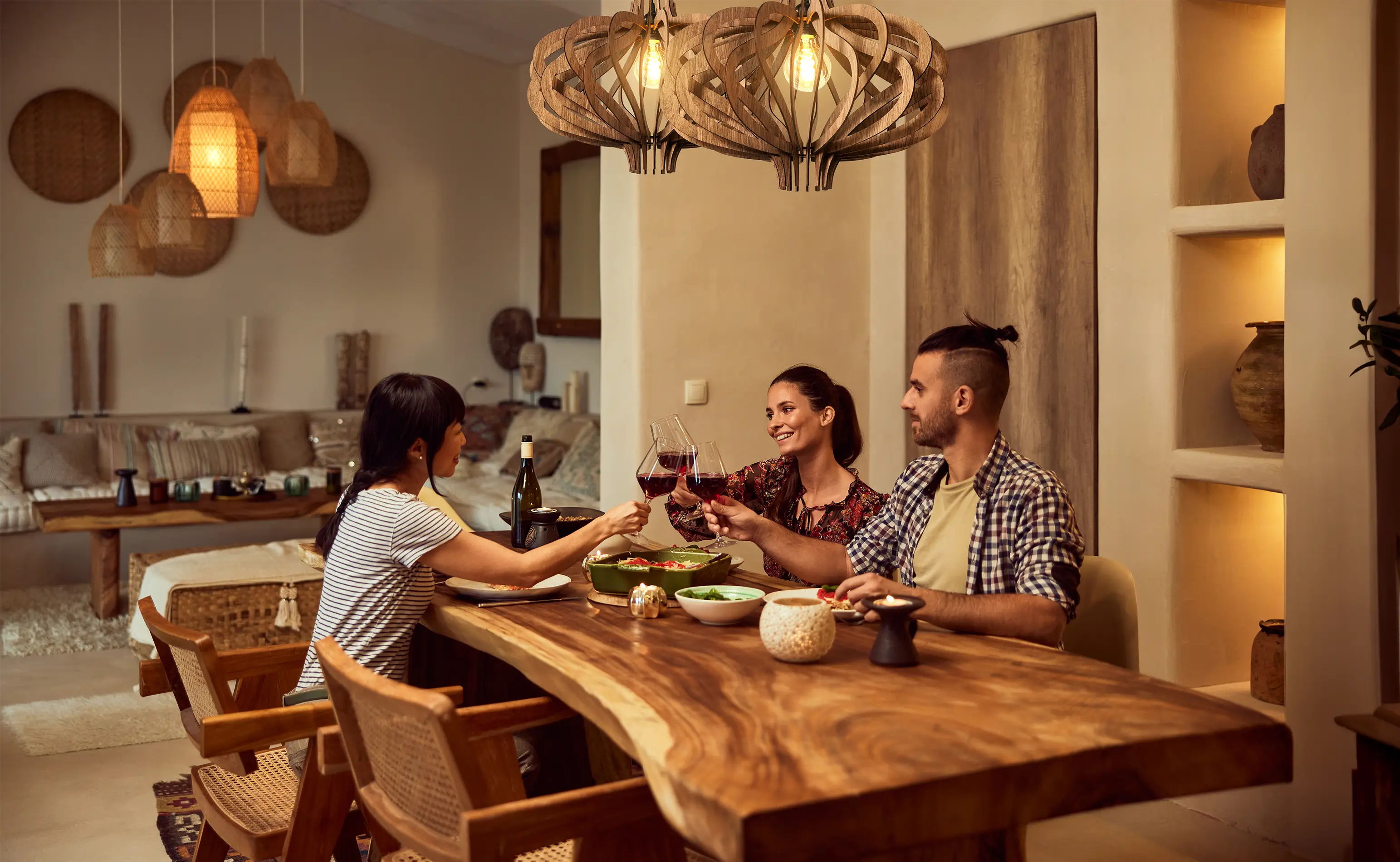 Friends enjoying a glass of wine at home under beautiful wooden pendant lights